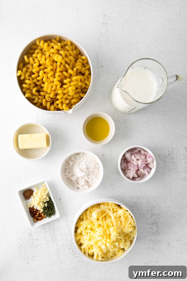 Creamy White Cheddar Mac 3 A selection of fresh ingredients laid out on a table, including pasta, shallots, garlic, thyme, and blocks of white cheddar cheese, ready to be prepared for homemade mac and cheese.