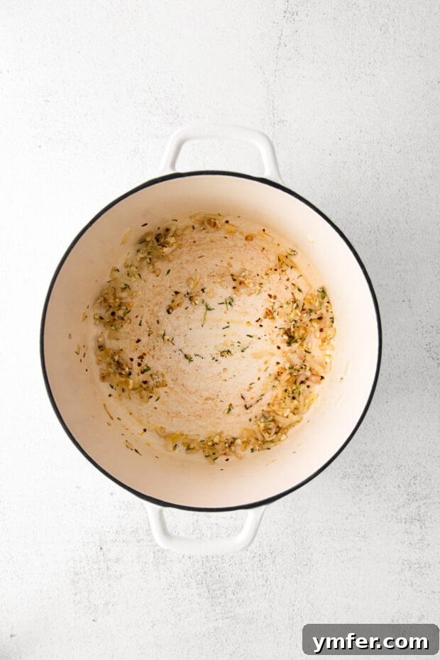 Creamy White Cheddar Mac 4 Minced shallots gently cooking in olive oil in a large Dutch oven, becoming tender and fragrant.