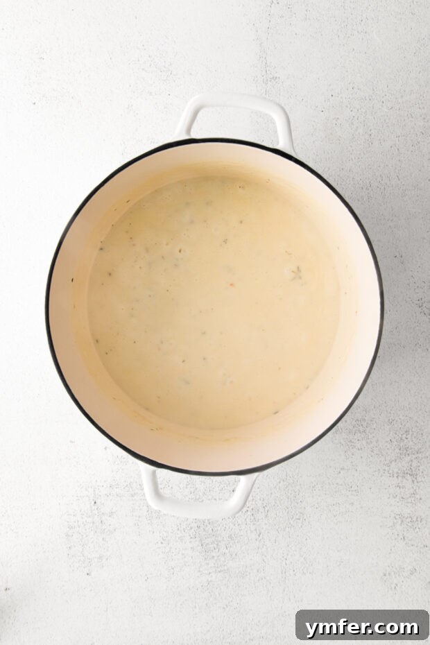 Creamy White Cheddar Mac 5 A creamy, smooth cheese sauce simmering in a Dutch oven, ready for the pasta.