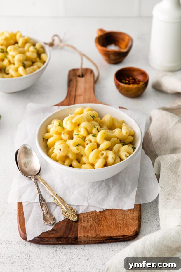 Creamy White Cheddar Mac 9 Two spoons dipping into a communal dish of White Cheddar Mac and Cheese, showcasing its inviting, creamy consistency.