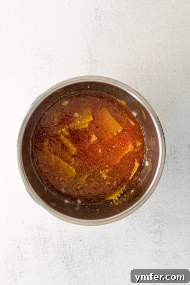 Easy Instant Pot Lasagna Soup 5 Uncooked Instant Pot Lasagna Soup ingredients layered in the Instant Pot before pressure cooking.
