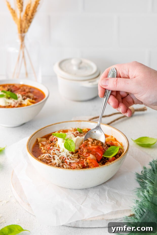 Easy Instant Pot Lasagna Soup 9 A spoon dipping into a bowl of Instant Pot Lasagna Soup, showing the rich texture.