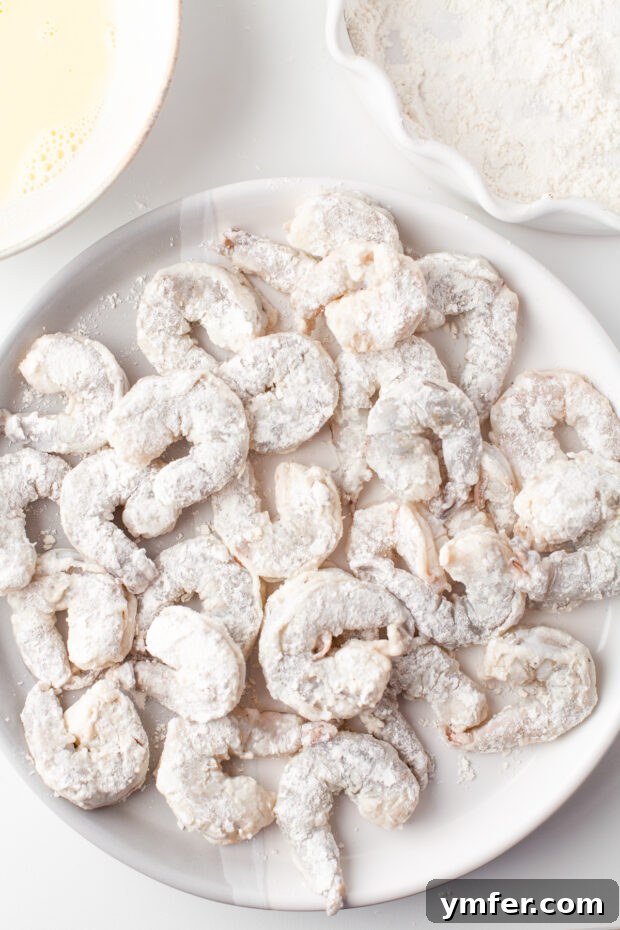 Golden Crispy Air Fryer Shrimp 5 Shrimp coated in a light layer of flour, ready for the next breading step.