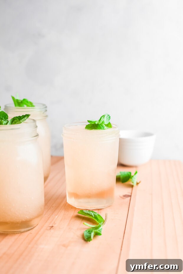 Kentucky Mint Slush 6 A Frozen Mint Julep cocktail in a clear glass, topped with abundant fresh mint leaves as garnish, highlighting its refreshing quality.