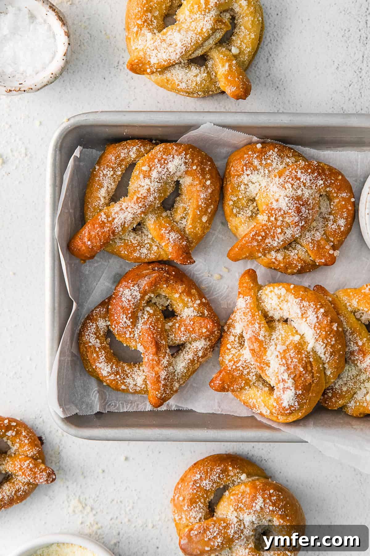 A close-up shot of garlic parmesan soft pretzels, beautifully garnished with extra grated cheese and herbs, on a platter.