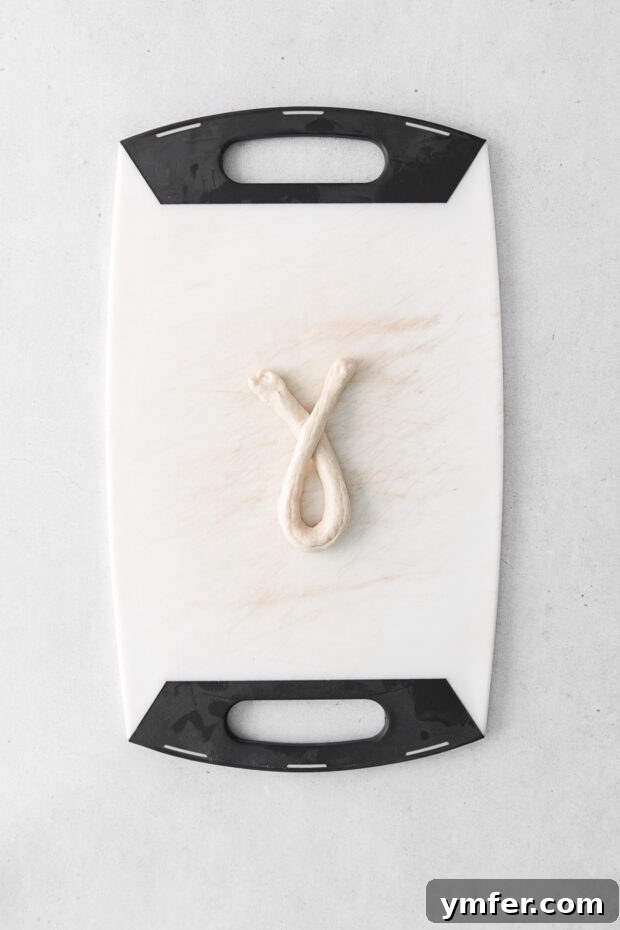 The pretzel dough being folded and twisted to form the classic pretzel shape.