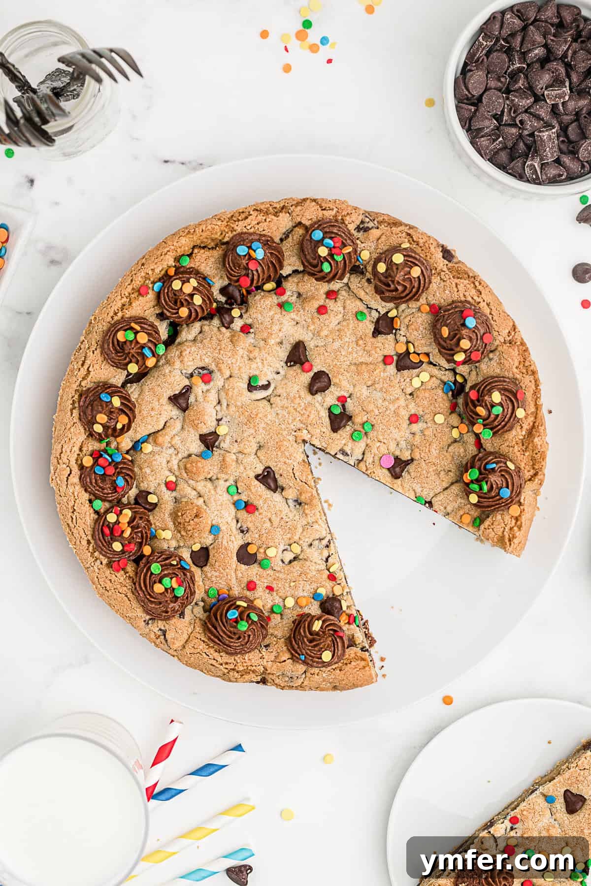 Ultimate Chocolate Chip Cookie Cake 11 A Chocolate Chip Cookie Cake with a single slice already removed, showcasing the remaining cake decorated with frosting and sprinkles.