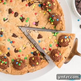 A baked Chocolate Chip Cookie Cake, beautifully decorated with chocolate frosting and colorful sprinkles.