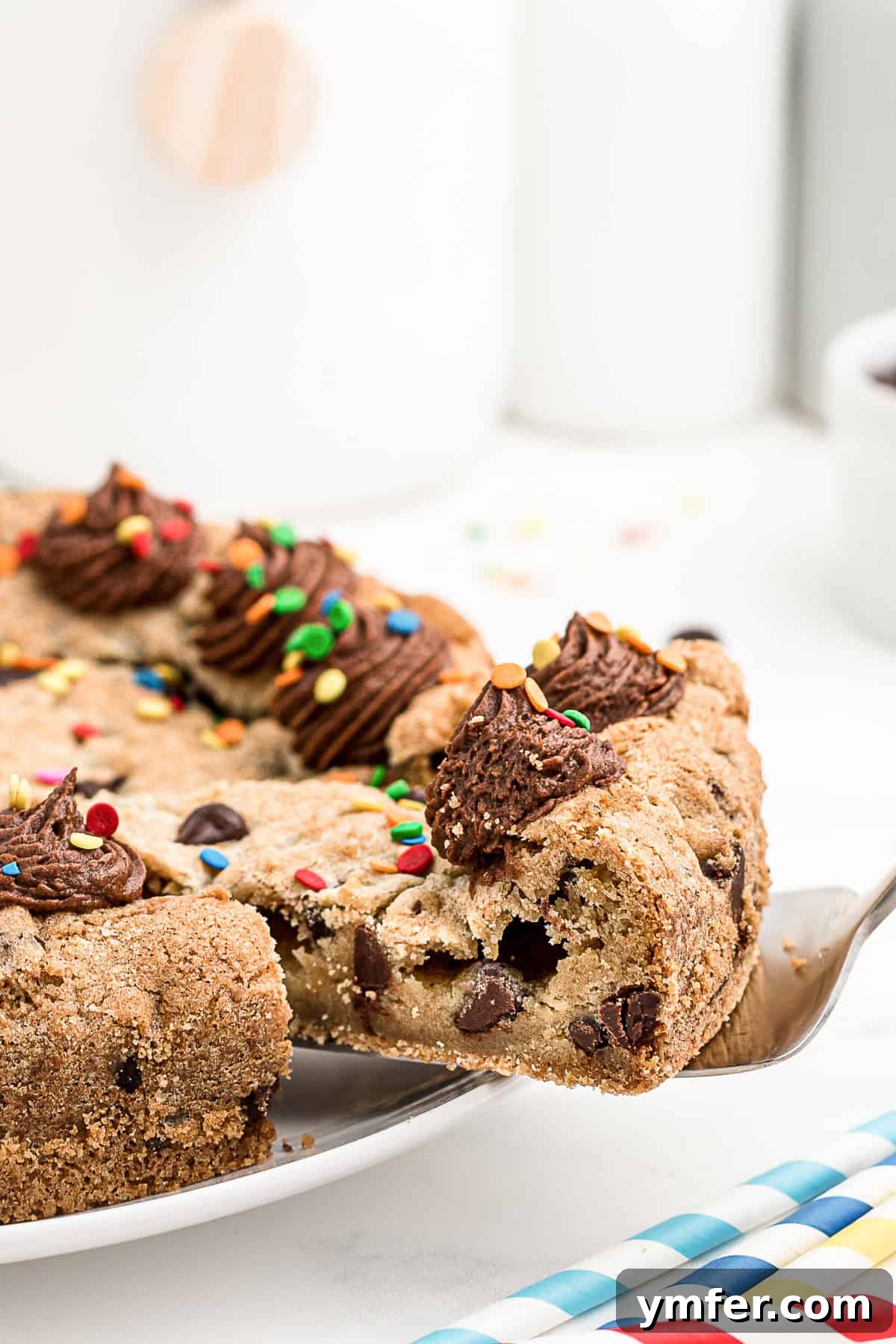 Ultimate Chocolate Chip Cookie Cake 8 A close-up, tempting shot of a single slice of Chocolate Chip Cookie Cake, showcasing its moist, chocolatey interior and rich frosting with sprinkles.