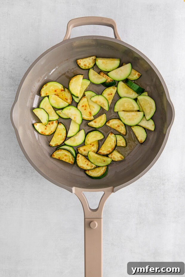 Bright Lemon Zucchini Pasta 4 Slices of zucchini cooking in a hot skillet, beginning to brown and soften.