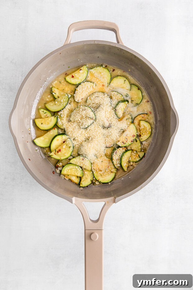 Bright Lemon Zucchini Pasta 5 Sautéed zucchini mixed with Parmesan cheese in a skillet, creating a creamy texture.