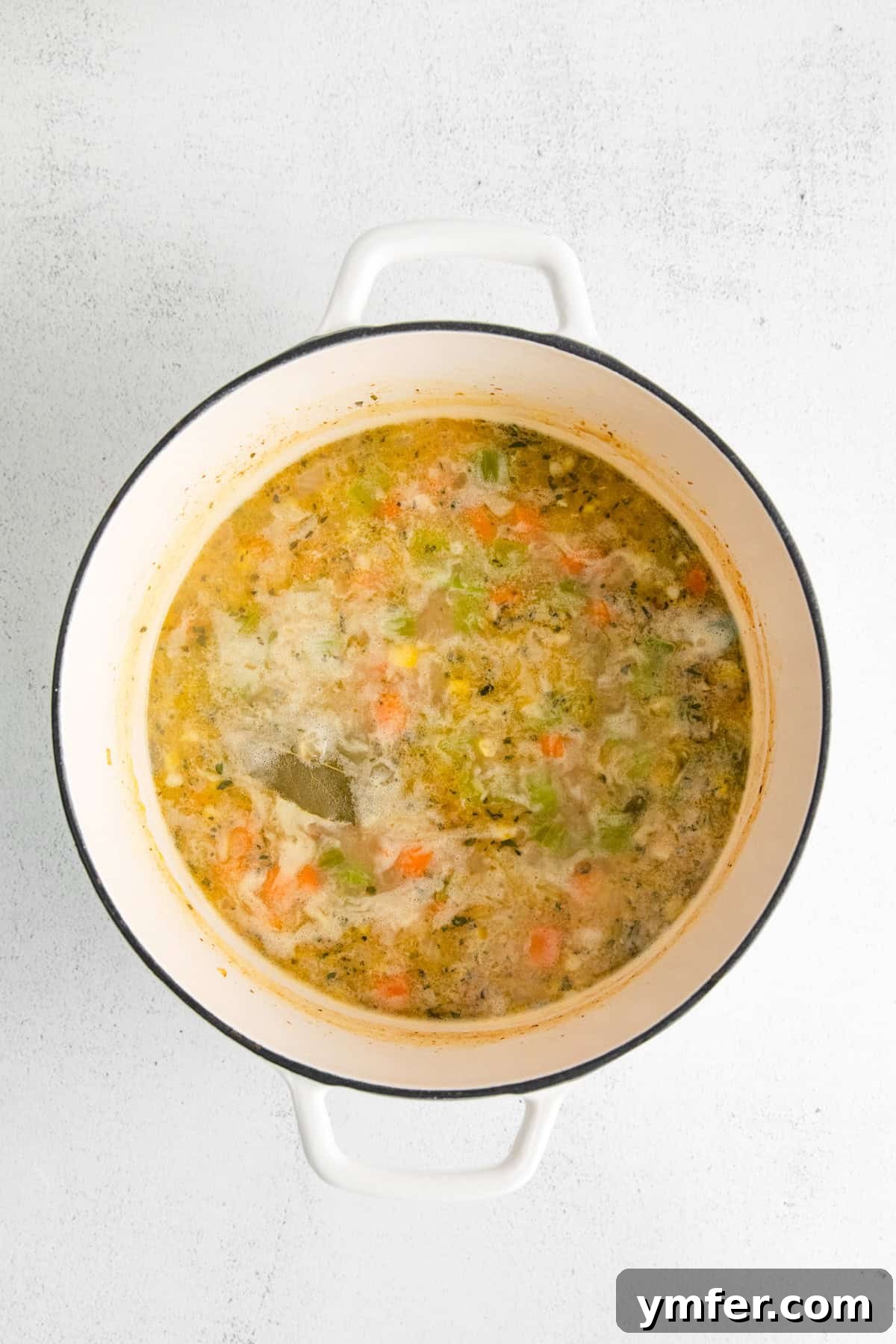 Golden Harvest Shrimp and Corn Chowder 6 A pot of simmering soup with a bay leaf visible, indicating the aromatic infusion.