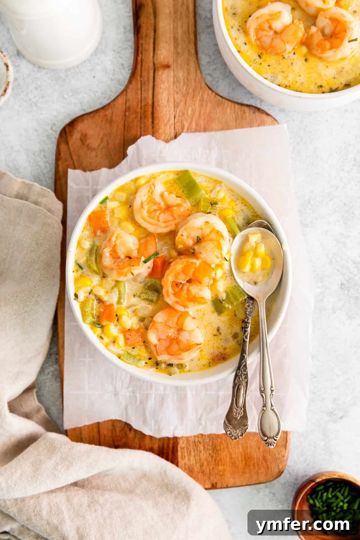 Golden Harvest Shrimp and Corn Chowder 8 A close-up of a bowl of Shrimp Corn Chowder with a spoonful being lifted, showcasing its creamy texture and visible ingredients.