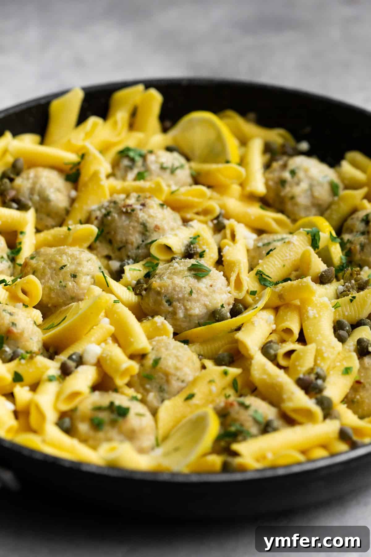 Tangy Lemon Caper Chicken Meatballs 4 Chicken piccata meatballs in a pan with the sauce.