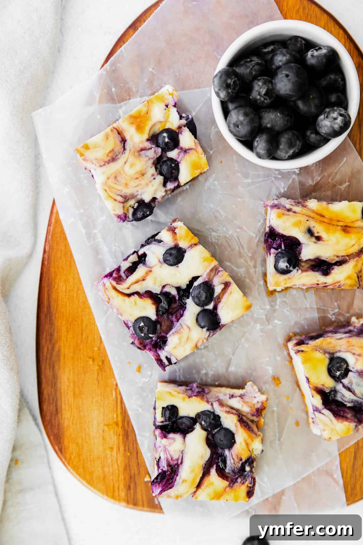 Luscious Blueberry Cheesecake Bars 2 Vibrant blueberry cheesecake bars arranged invitingly on a serving tray, showcasing their rich purple swirls and golden crust.