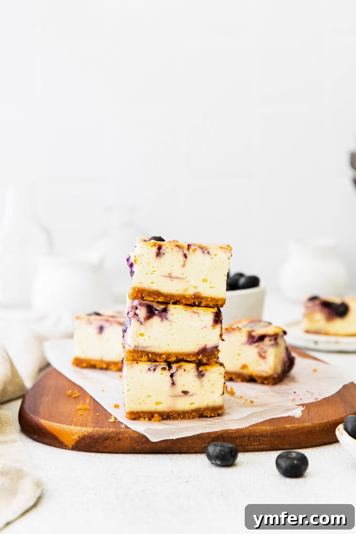 Luscious Blueberry Cheesecake Bars 6 Multiple blueberry cheesecake bars stacked artfully, showcasing their thickness and the rich, swirled filling.