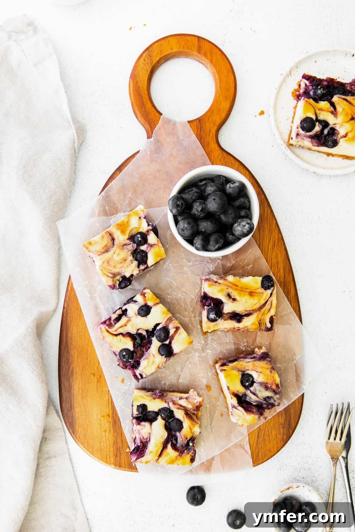 Luscious Blueberry Cheesecake Bars 8 Blueberry cheesecake bars elegantly arranged on a rustic wooden serving board, inviting guests to enjoy.