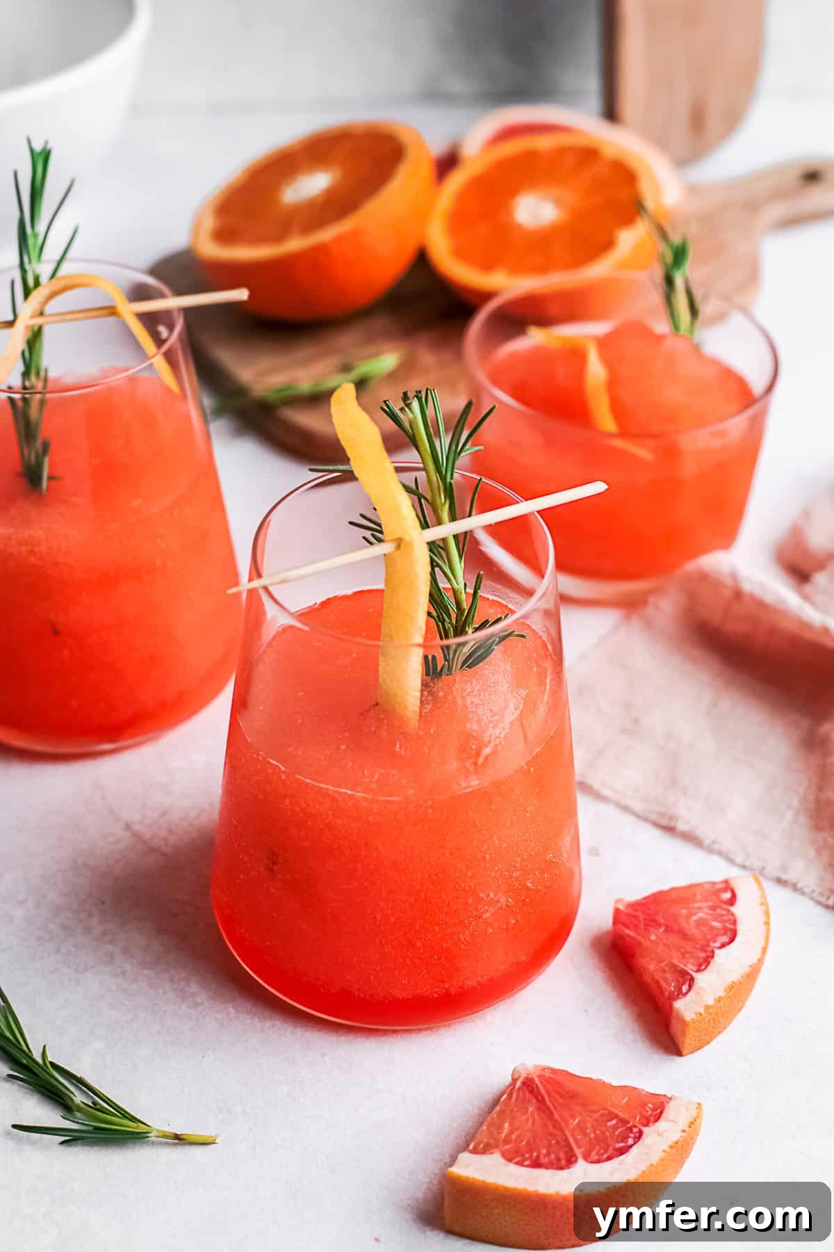 Slushy Aperol Bliss 2 Frozen Aperol Spritz in a cocktail glass garnished with orange and rosemary.