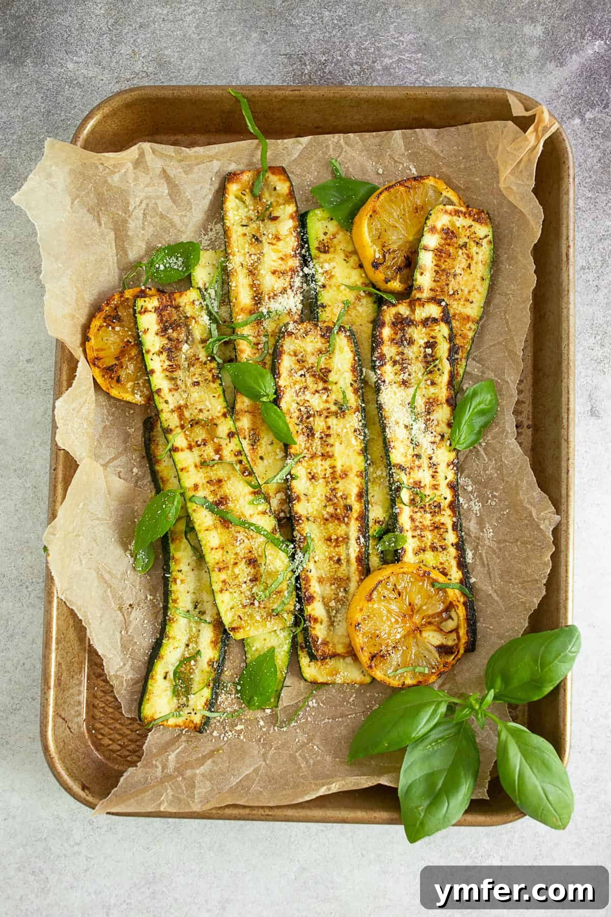 Fire-Kissed Zucchini 2 Grilled Zucchini on a sheet pan, seasoned with herbs and topped with fresh lemon.