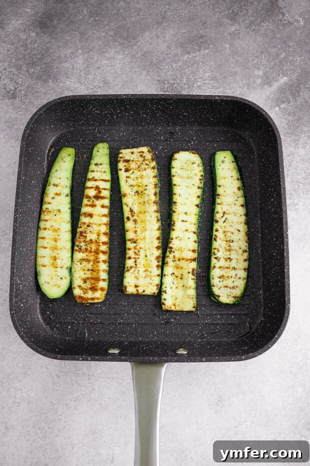 Fire-Kissed Zucchini 5 Grilled zucchini cooking on a grill pan, showing developing char marks.