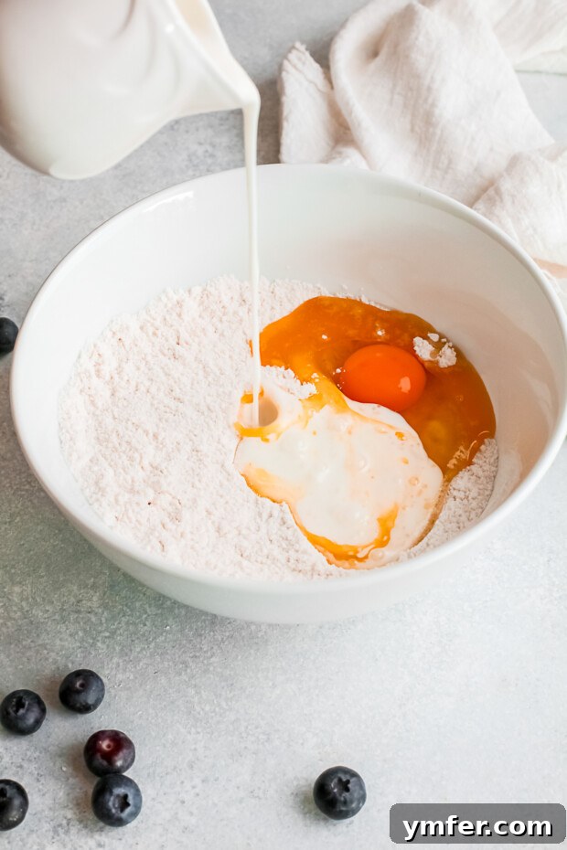 Pouring buttermilk into a mixing bowl of donut batter ingredients.