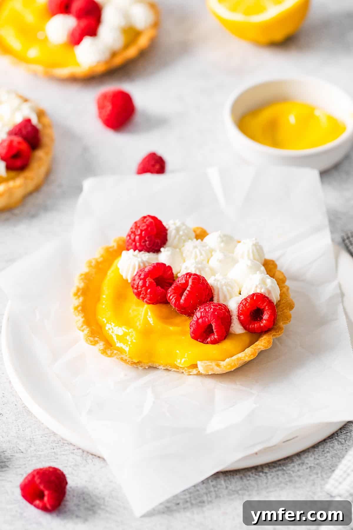 Sunshine Lemon Tarts 7 A close-up of a perfectly formed lemon curd tart, topped with vibrant fresh berries, emphasizing its inviting texture and color.