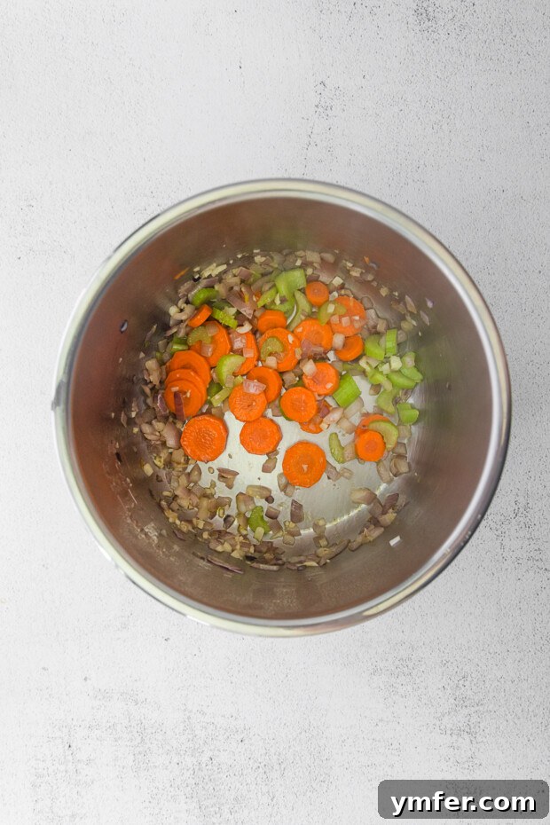 Effortless Instant Pot Tomato Delight 4 Vegetables in an instant pot. Chopped carrots, shallots, and celery are sautéing in olive oil at the bottom of an Instant Pot, turning slightly translucent.