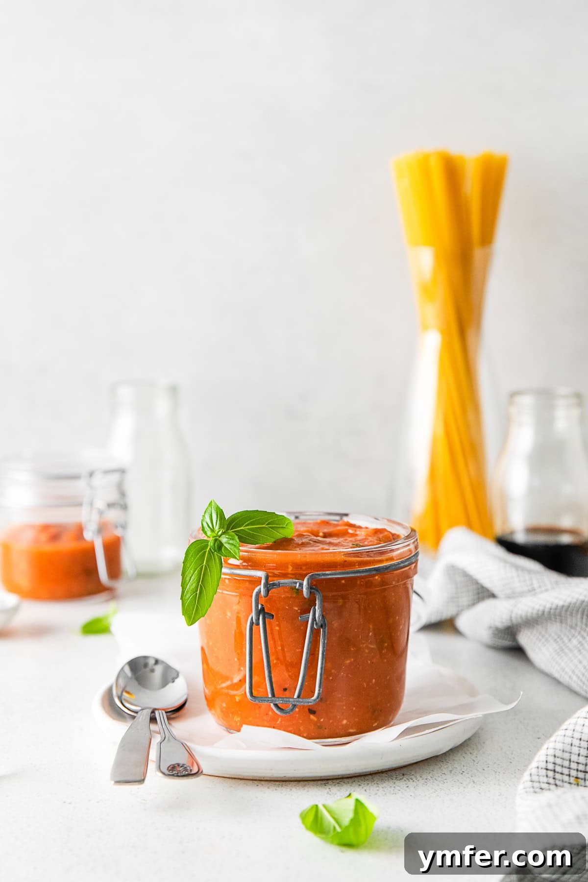 Richly Roasted Tomato Sauce 2 Freshly made Roasted Tomato Sauce in a glass jar, garnished with fresh basil leaves. The sauce has a rich, deep red color.