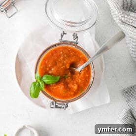 Richly Roasted Tomato Sauce 12 A glass jar of Roasted Tomato Sauce with a spoon resting in it.
