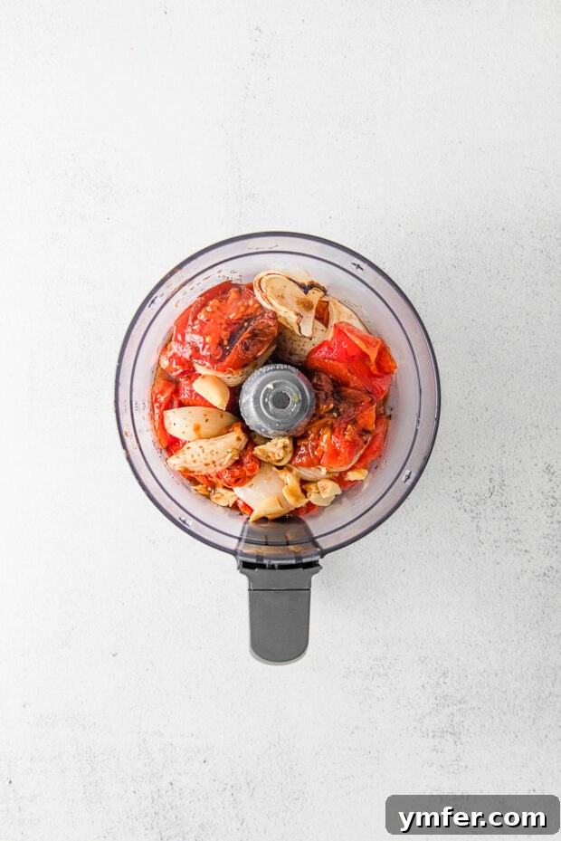 Richly Roasted Tomato Sauce 6 Roasted tomatoes and onions, along with a head of roasted garlic, transferred to a food processor bowl, ready for blending.