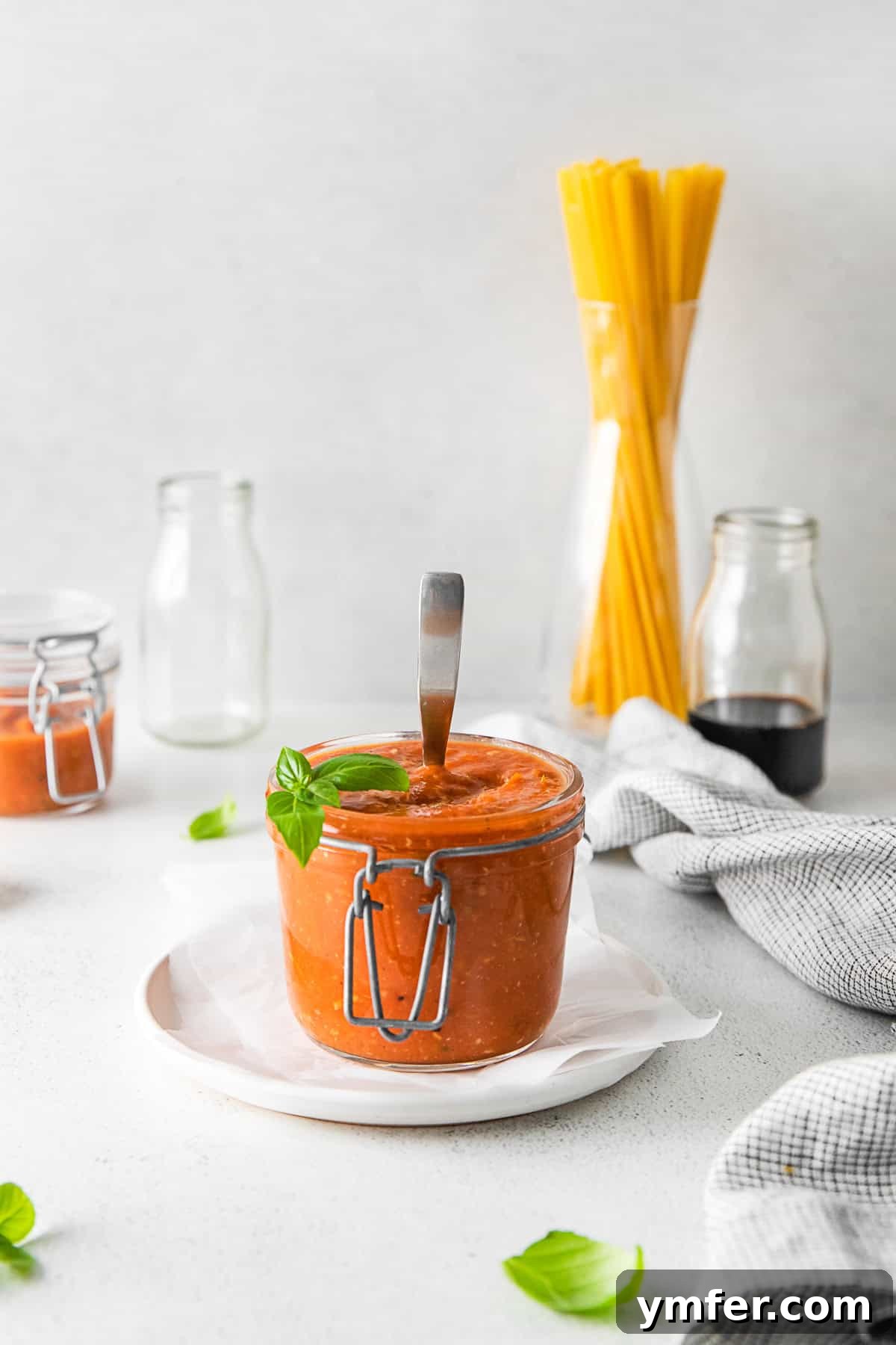 Richly Roasted Tomato Sauce 10 A glass jar of Roasted Tomato Sauce with a spoon inside, ready for storage or immediate use.