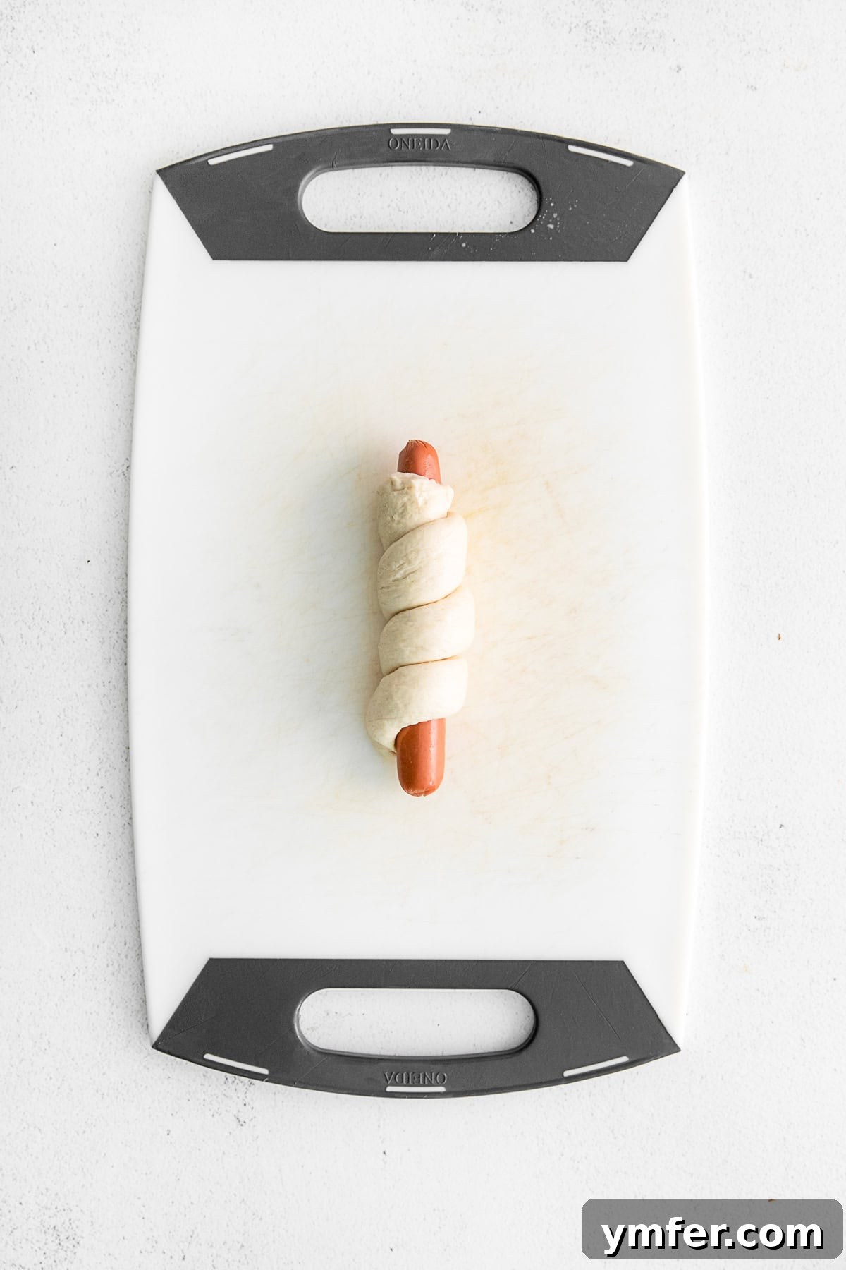 Golden Pretzel Franks 4 Soft pretzel dough expertly wrapped around a hot dog, ready for the next step of preparation.