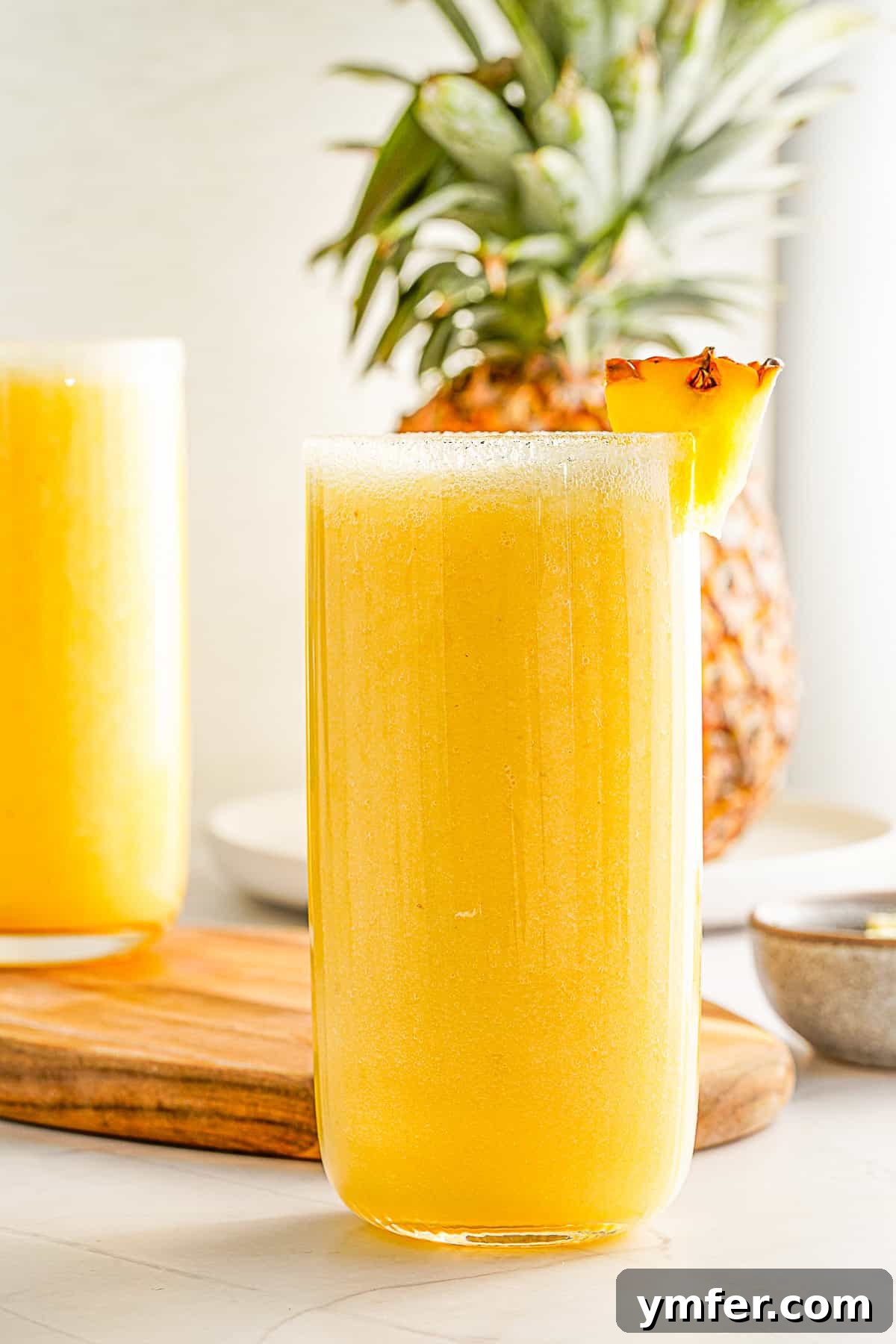 Tropical Mango Pineapple Bliss 2 Mango Pineapple Smoothie in a glass with fresh lime and pineapple as garnish, perfectly capturing a tropical vibe.