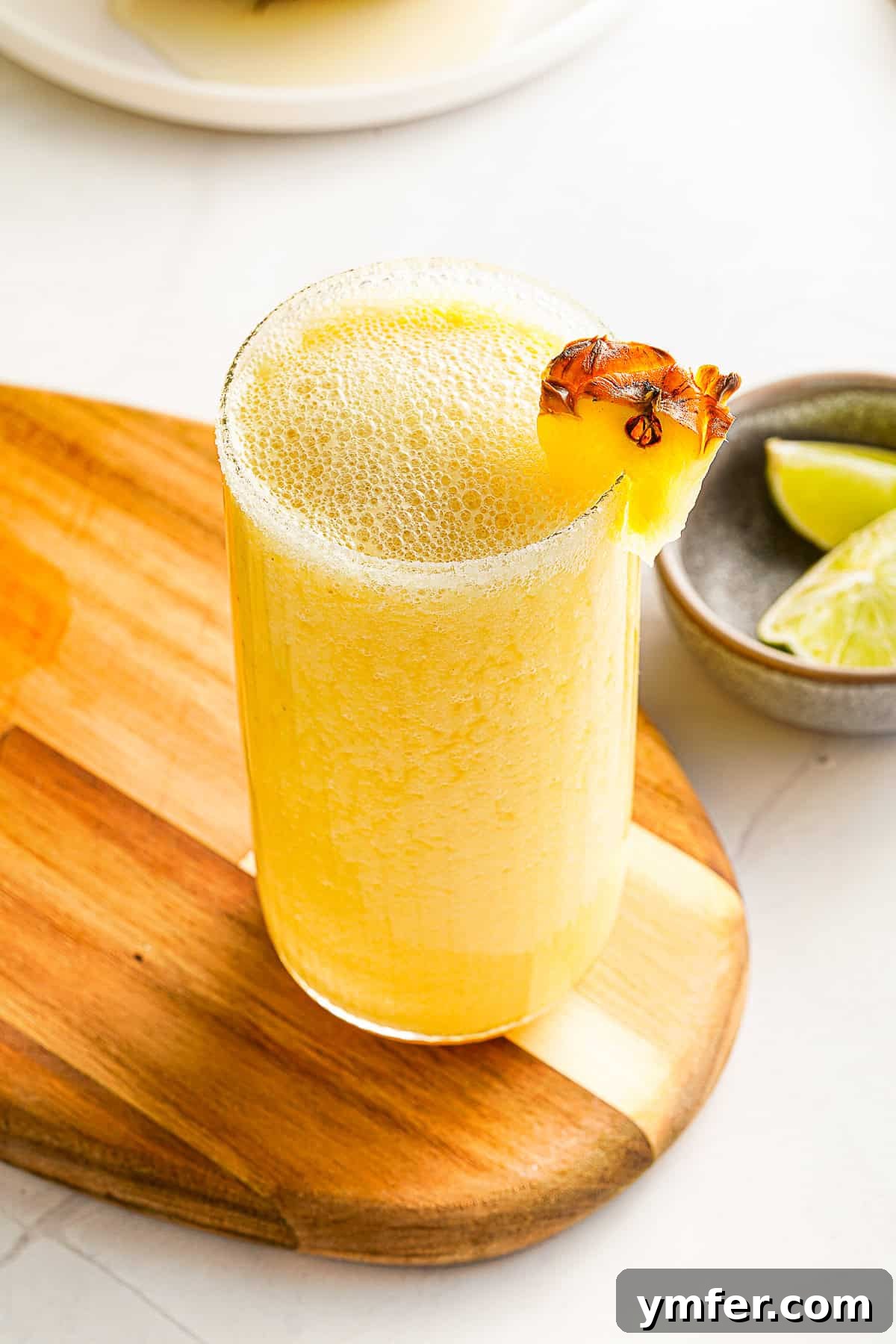 Tropical Mango Pineapple Bliss 8 Mango Pineapple Smoothie in a glass, garnished with a pineapple wedge on the rim, showcasing its appeal.