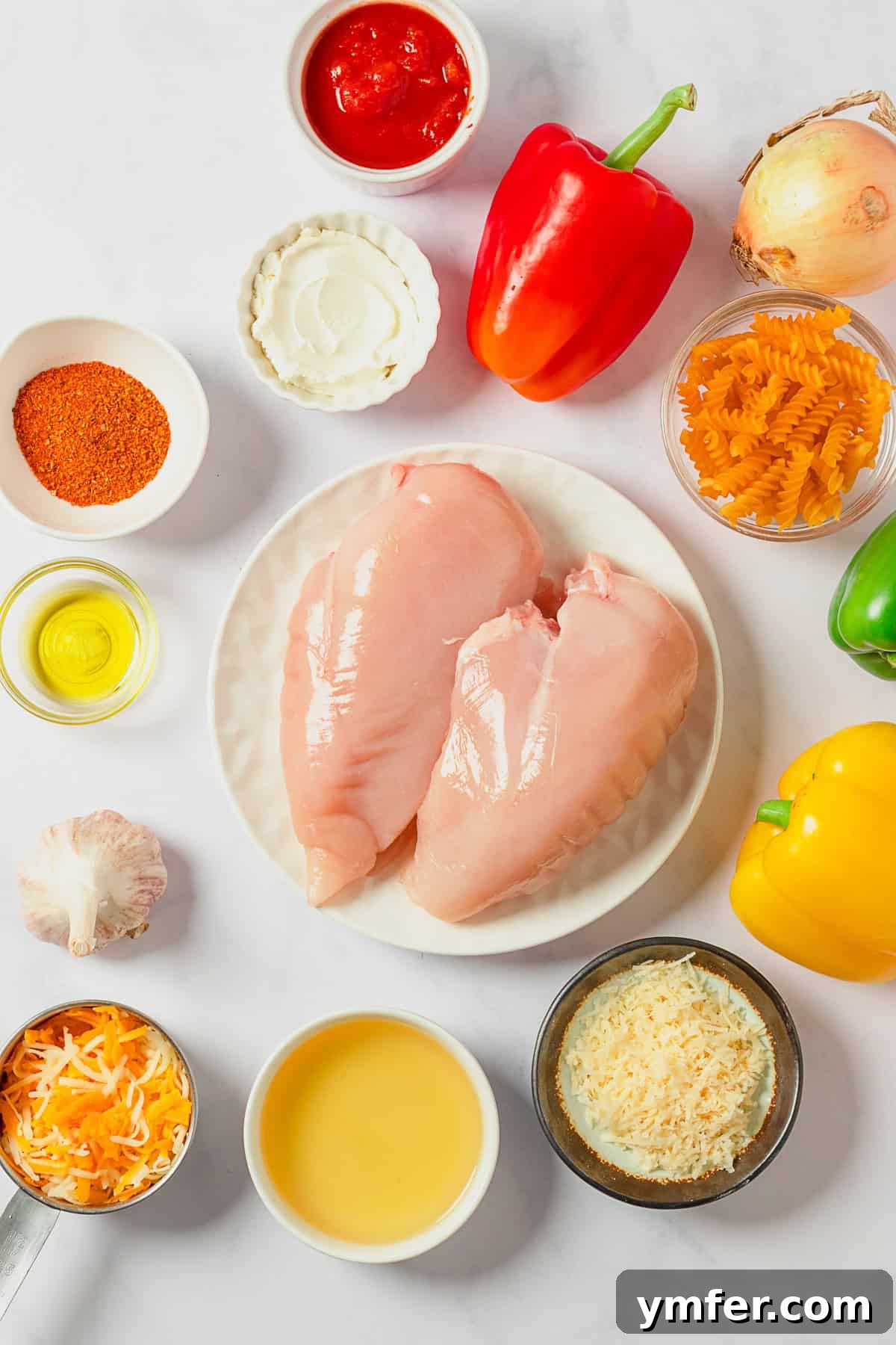 Zesty Skillet Chicken Fajita Pasta 3 Ingredients for One Pot Chicken Fajita Pasta laid out on a cutting board, including chicken breast, bell peppers, onion, and spices.