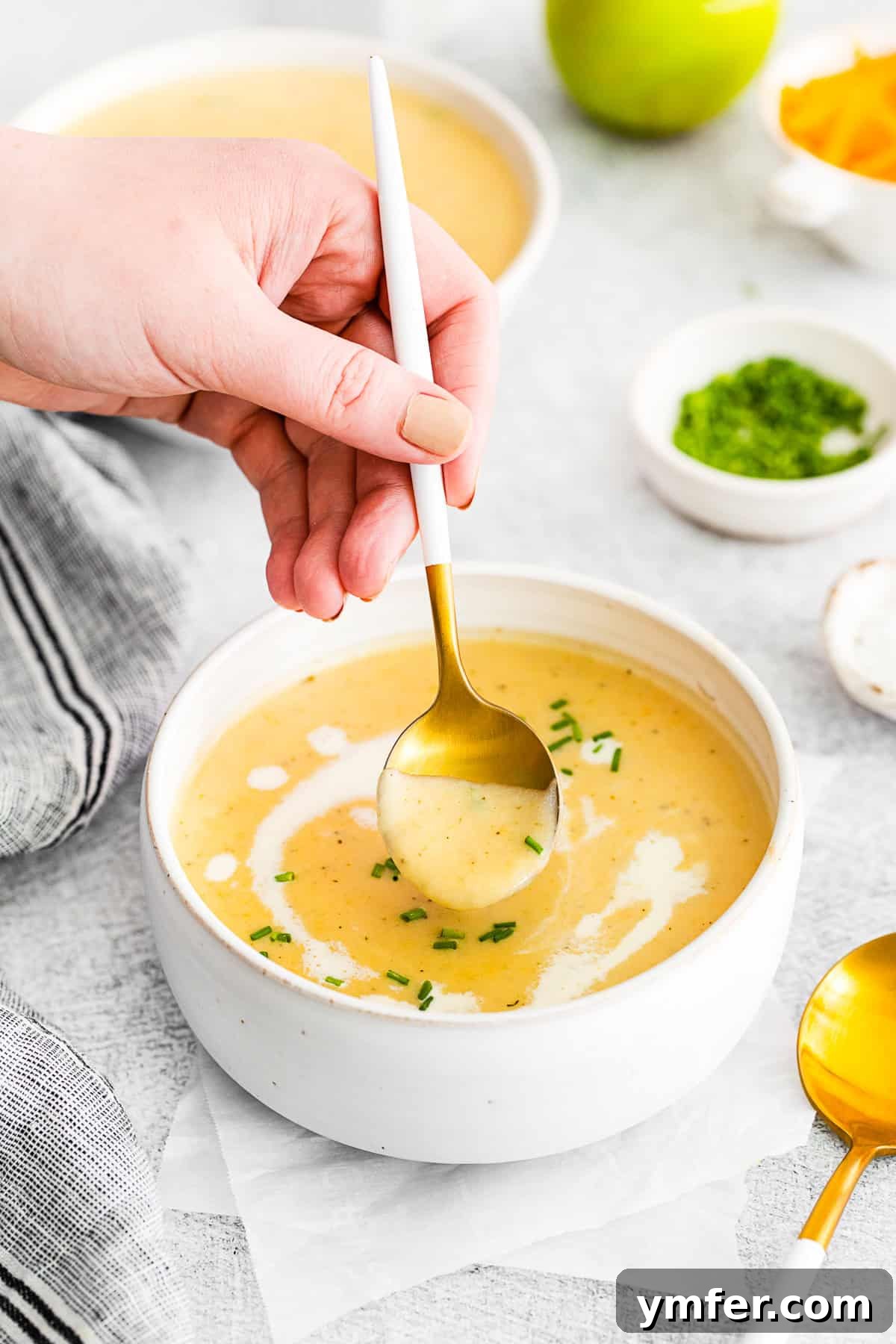 Creamy Cheddar Apple Harmony 4 A hand spooning out a bite of Apple Cheddar Soup.