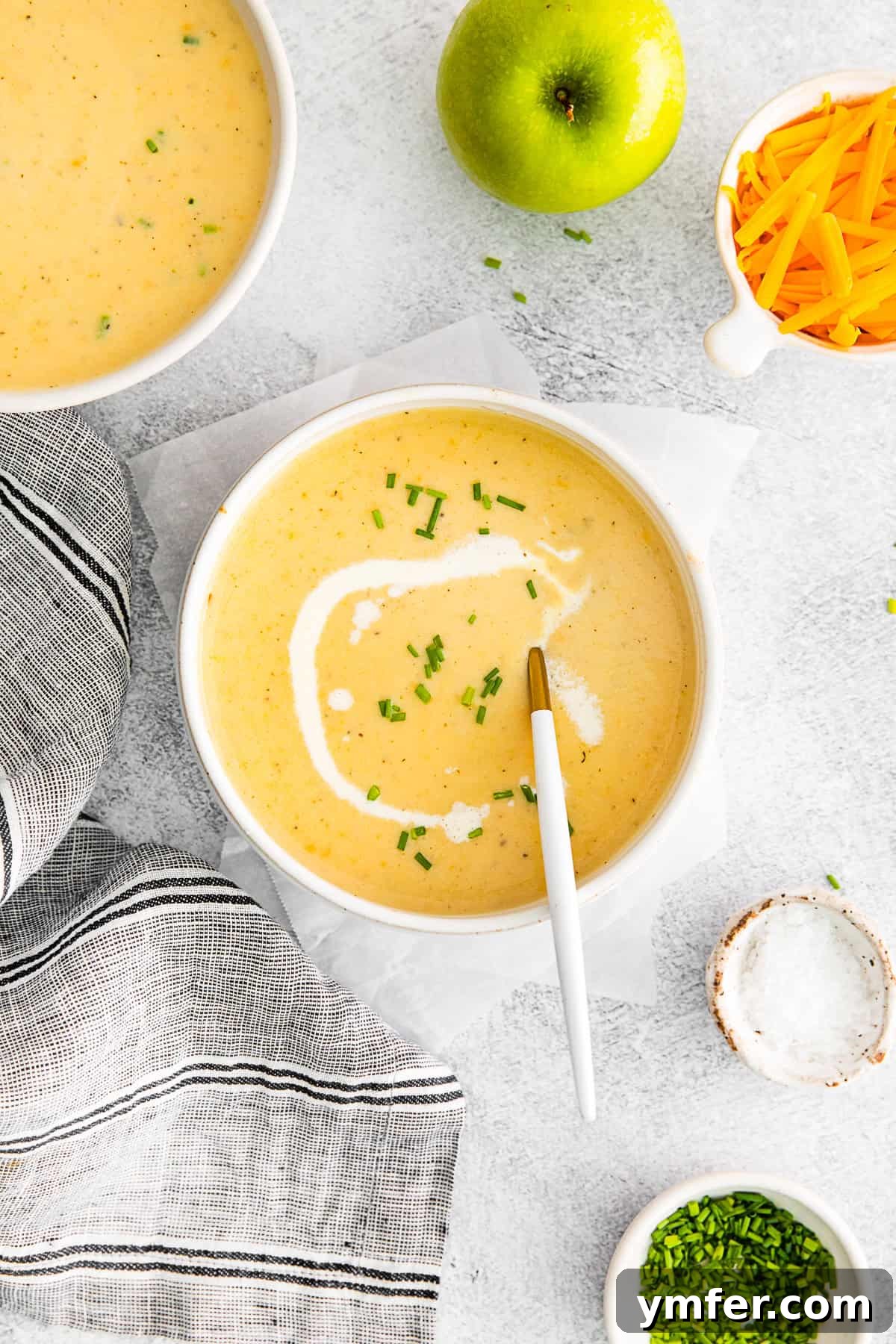 Creamy Cheddar Apple Harmony 5 Apple Cheddar Soup in a bowl with a spoon.