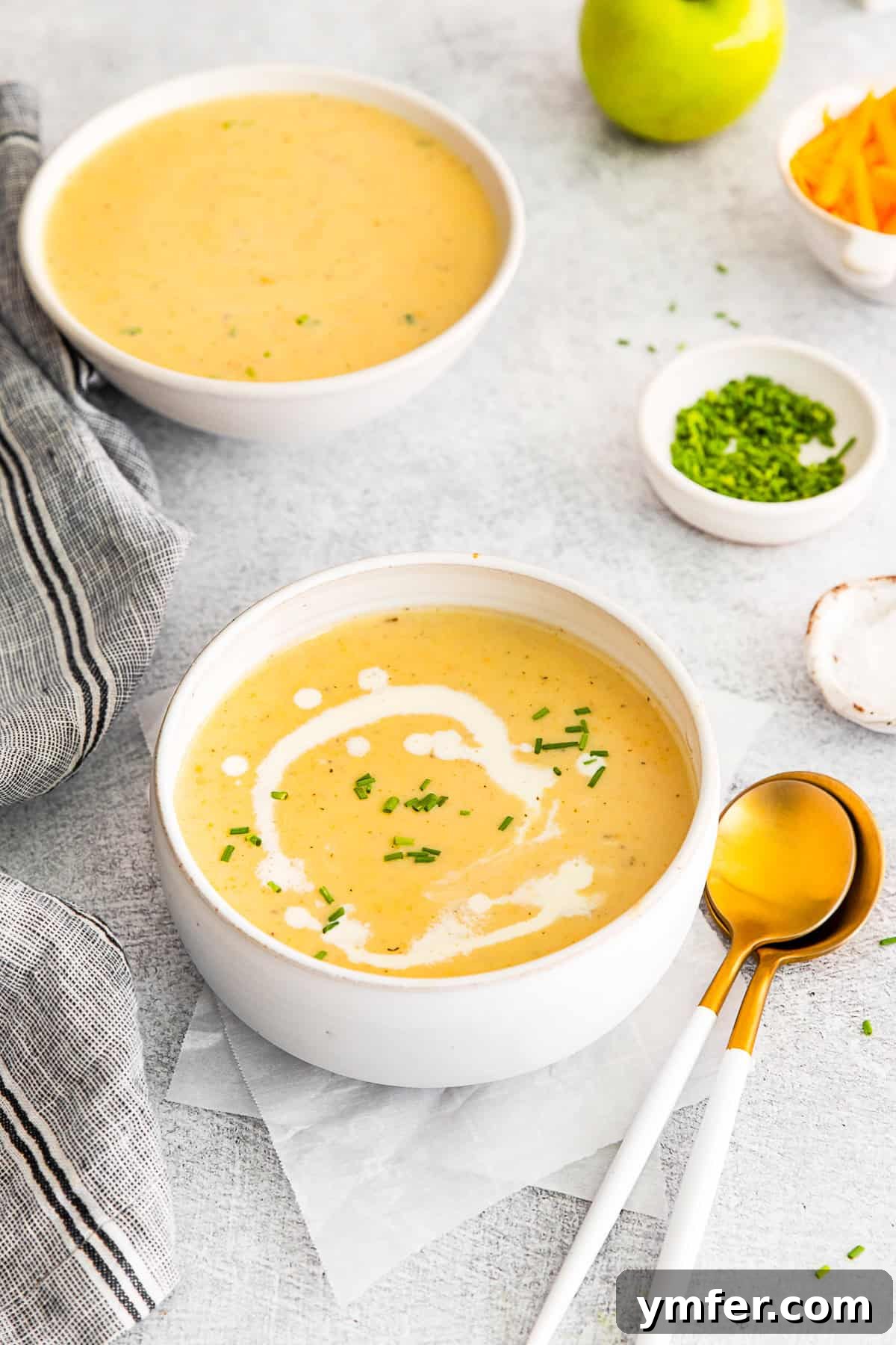 Creamy Cheddar Apple Harmony 6 Apple Cheddar Soup sitting on a table with another bowl of soup in the background.