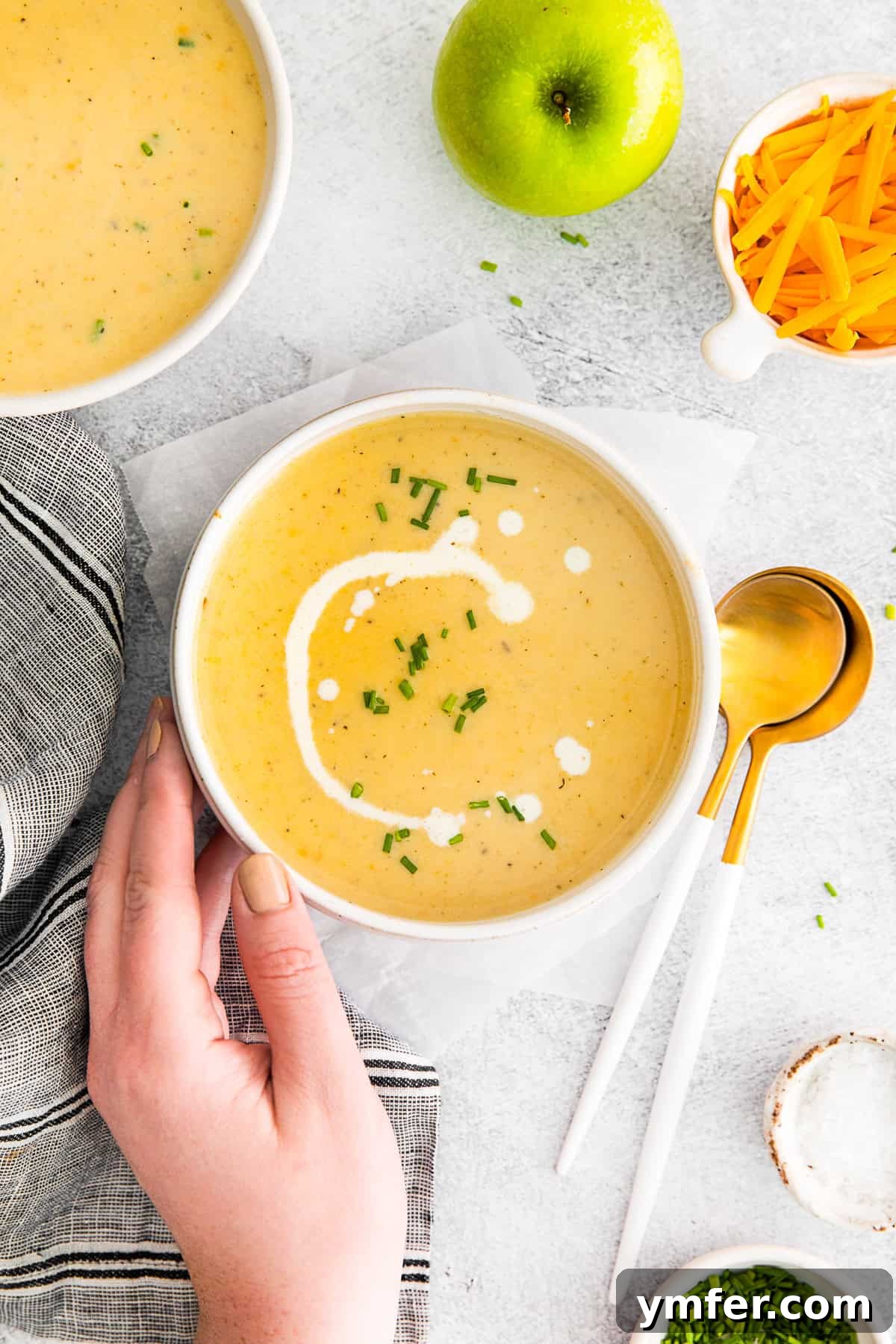 Creamy Cheddar Apple Harmony 7 Apple Cheddar Soup with a hand holding the bowl.