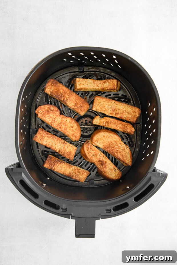 Golden-brown Air Fryer French Toast Sticks nestled in a single layer within the air fryer basket, showcasing their perfectly crispy texture.