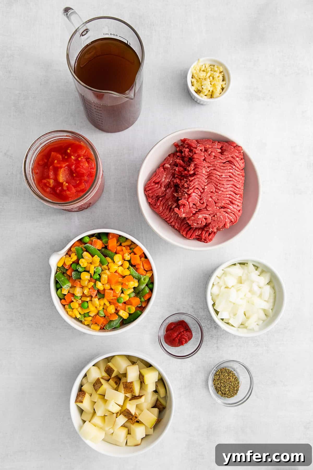 Beef Vegetable Soup 3 Ingredients for Vegetable Beef Soup laid out on a rustic wooden table.