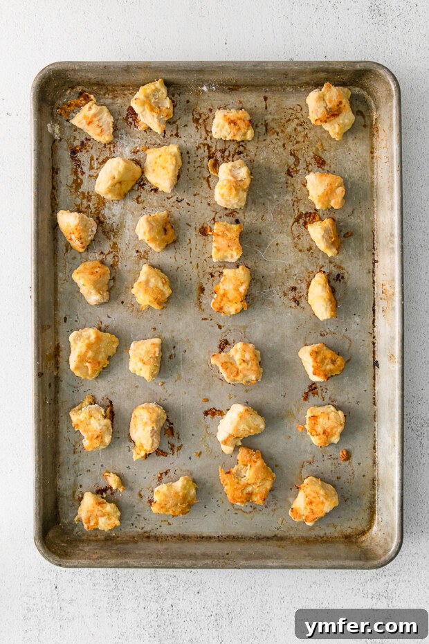 Simple Sheet Pan Sticky Orange Chicken 4 Cooked chicken pieces neatly arranged on a sheet pan.
