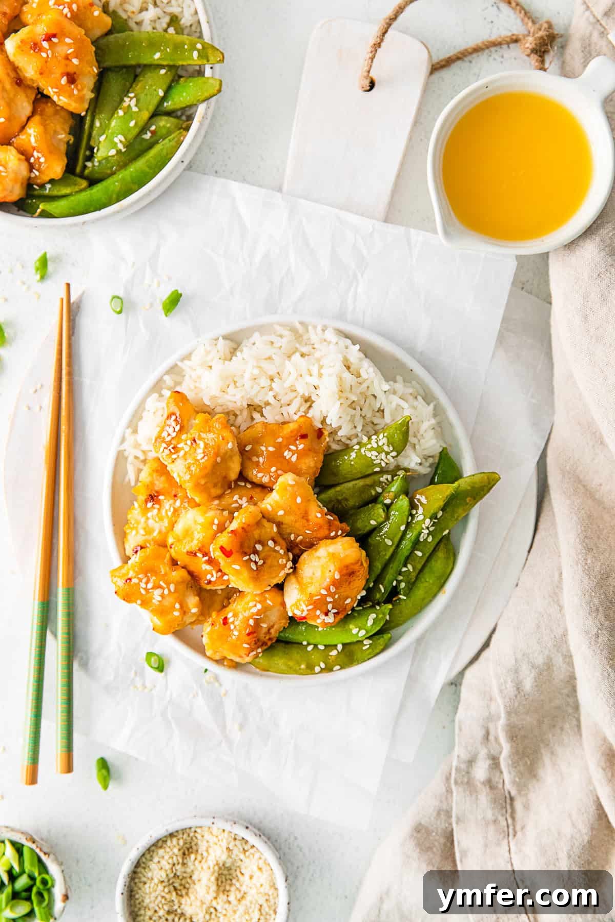 Simple Sheet Pan Sticky Orange Chicken 7 Sheet Pan Orange Chicken served with chopsticks and garnished with sesame seeds.