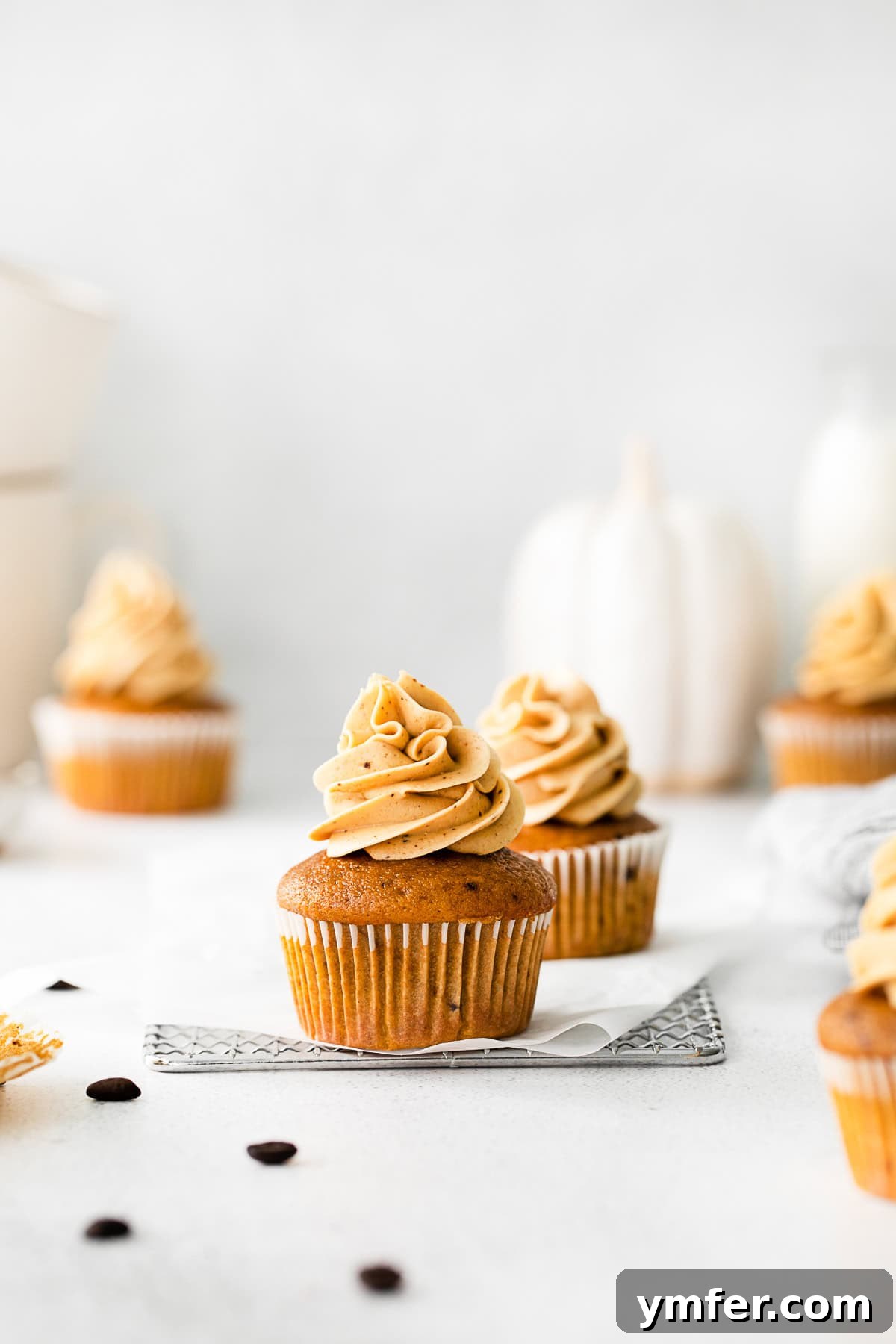 Beautifully decorated Pumpkin Spice Latte Cupcakes arranged on a rustic wooden table, ready to be enjoyed.