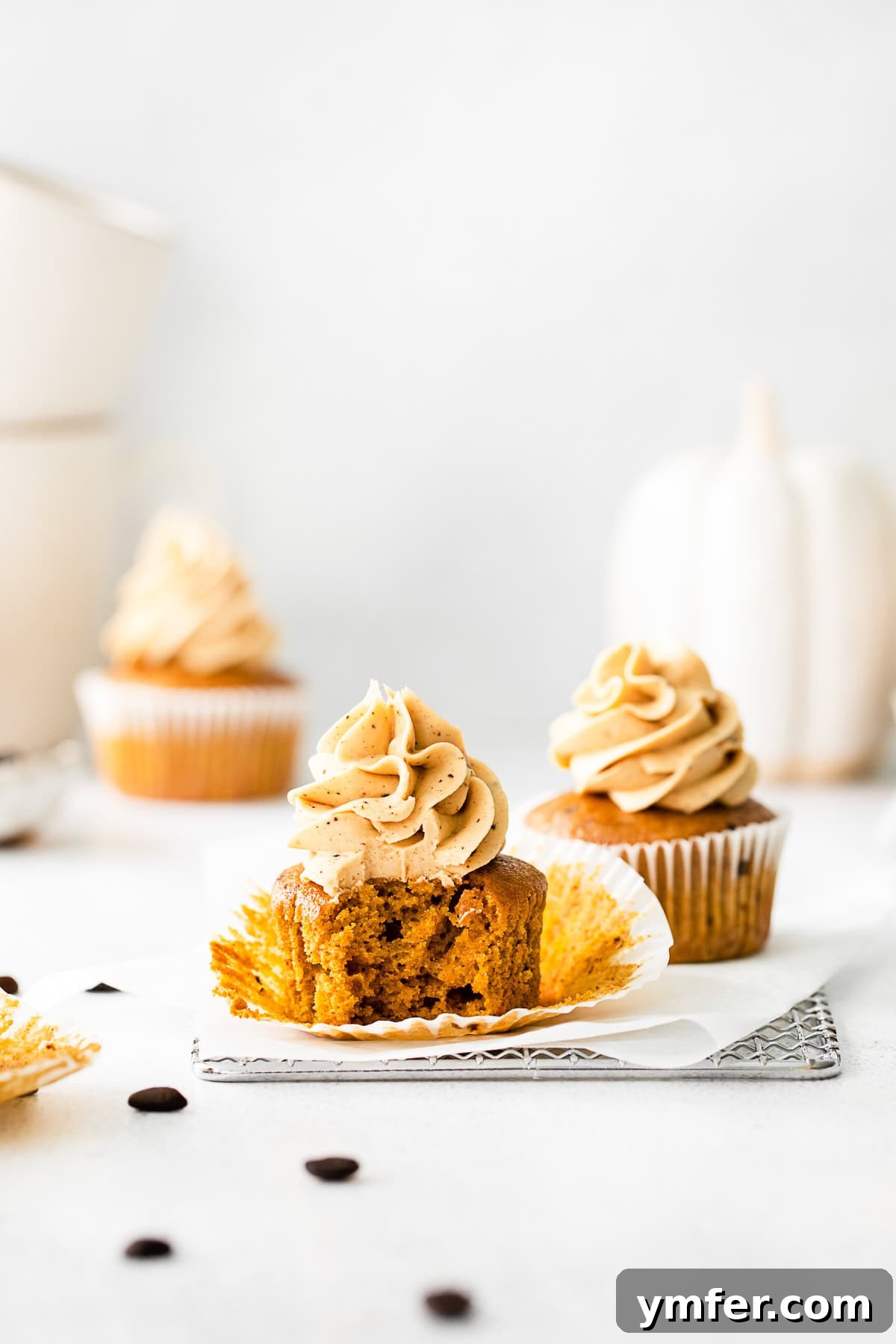 A Pumpkin Spice Latte Cupcake with a bite taken out of it, revealing its moist interior and generous frosting.