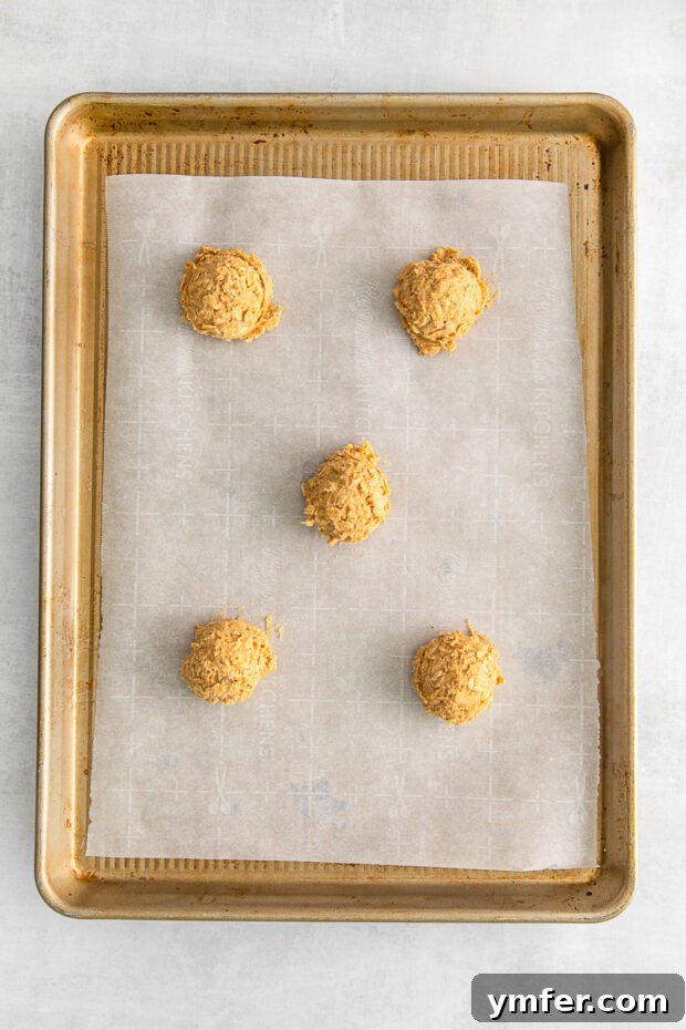 Autumn Spice Oatmeal Delights 6 Uncooked Pumpkin Oatmeal Cookies on a sheet pan.