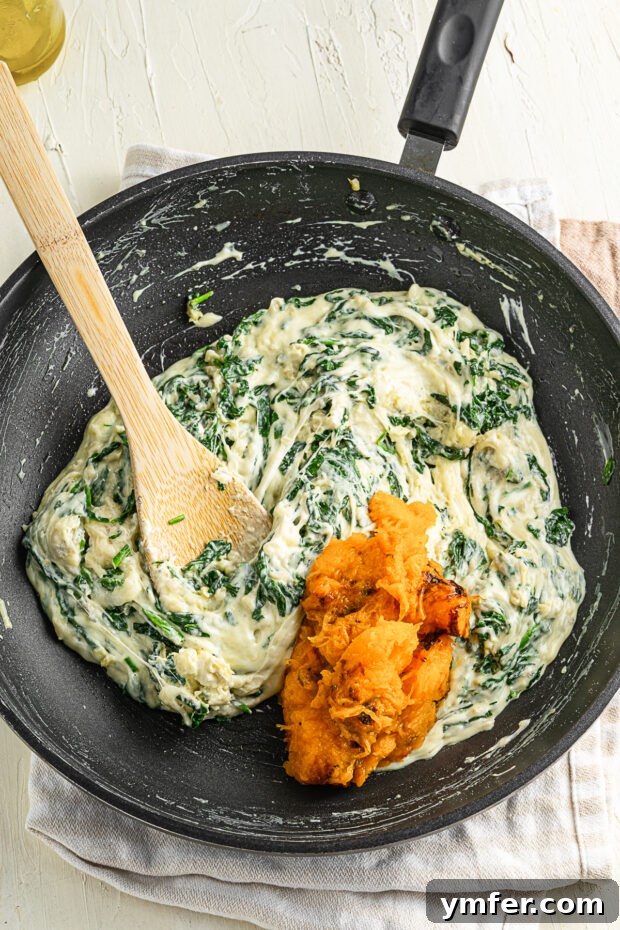 Creamy Cheesy Butternut Squash Bake 5 Close-up of the rich cheese and spinach mixture being combined with scooped butternut squash flesh.