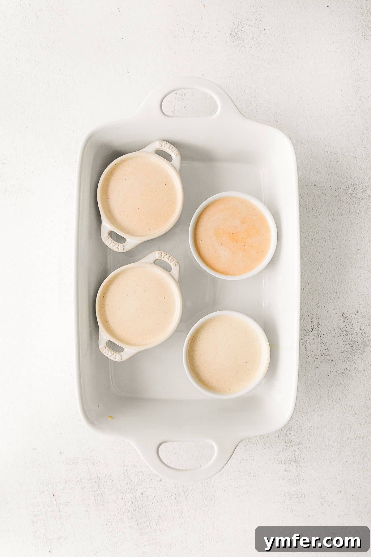 Spiced Pumpkin Creme Brulee 8 Uncooked pumpkin creme brulee batter in ramekins, placed in a baking dish before the water bath.