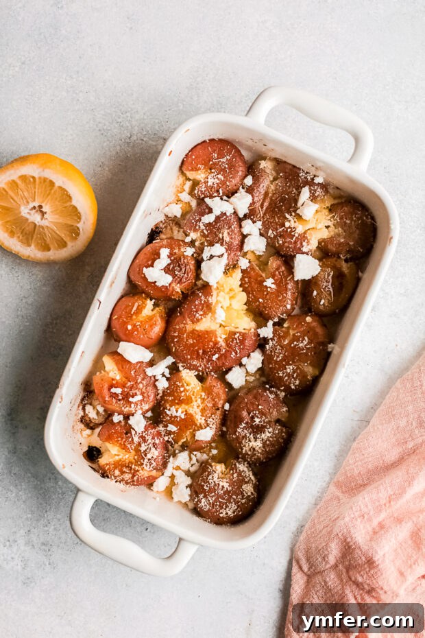 Golden Gooey Smashed Potatoes 7 Smashed potatoes topped with crumbled feta and grated Parmesan cheese, unbaked, in a white dish.