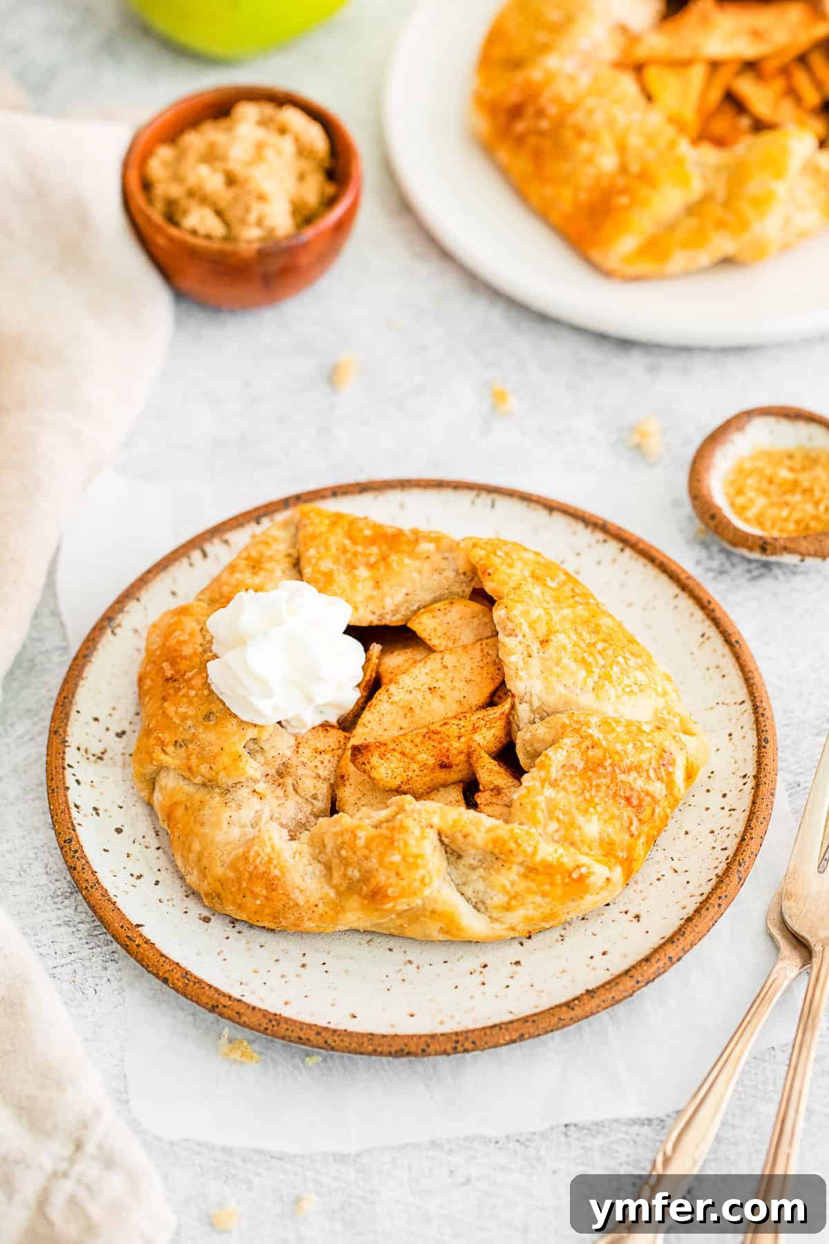 A freshly baked Apple Galette topped with a generous swirl of whipped cream.